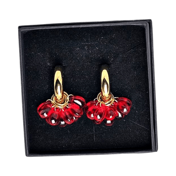 Punaiset korvakorut kullanvärisellä yksityiskohdalla